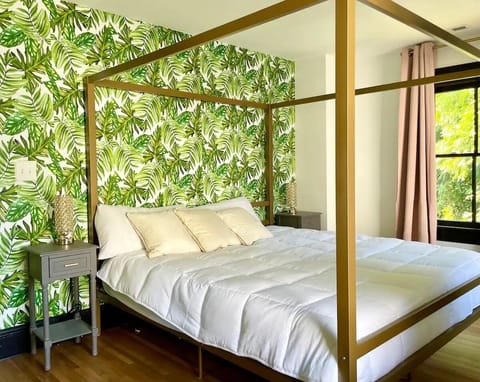 Guest Bedroom #2 with tropical themed gold canopy bed and palm leaf accent wall