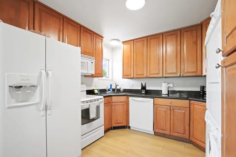 The charming kitchen boasts ample cabinets, modern black countertops, bright, white appliances, including a stacked washer and dryer, and everything you need to feel at home from a toaster to a coffee maker.