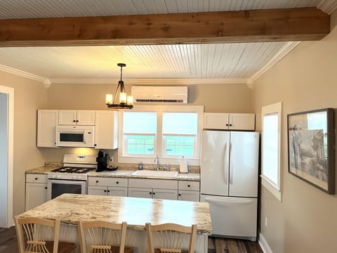 Kitchen with island seating, full fridge, gas stove and all dishes, cookware.