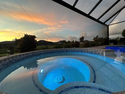 Relaxing pool with a spa section, enclosed in a lanai for sunset views