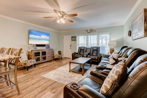 Relax in your spacious living room with plush leather seating, beach-themed decor, and entertainment center for memorable evenings together.