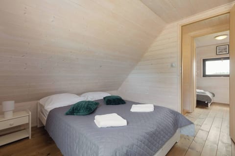 A small but inviting bedroom featuring a double bed with soft linens and a bedside table. The wooden interior adds warmth and a homely touch. The room feels intimate and perfect for unwinding.