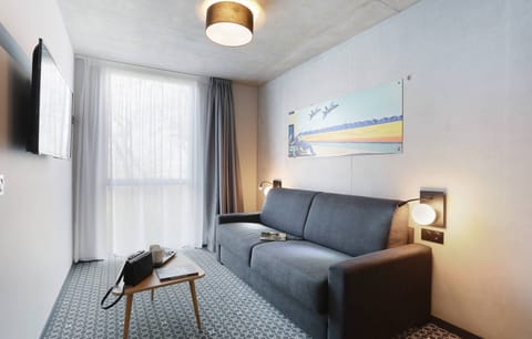 The bright living area features a TV and a comfy couch.