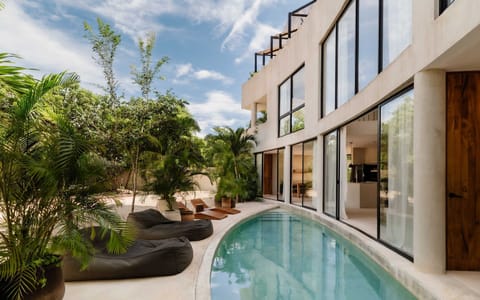 A private garden pool framed by palms and tropical architecture.
