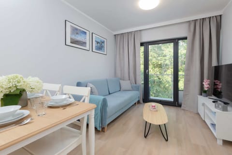 A bright and cozy living area with a comfortable sofa, a wooden coffee table, and large windows bringing in natural light.
