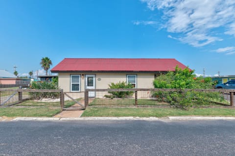 Charming single-story home with red corrugated roof and fenced yard in quiet residential neighborhood.