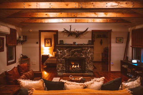 View of the fireplace from the dining table. Rustic wood beams across the living room
