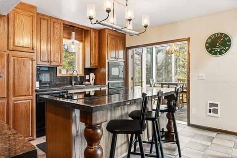 Your gourmet kitchen features granite countertops, rich oak cabinetry, and a breakfast bar perfect for morning coffee while enjoying forest views through the large windows.