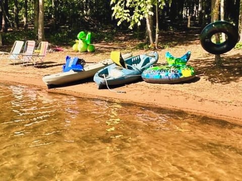 Sandy beach with kayaks, floats and chairs.
