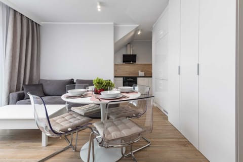 A bright dining area with a round table, two chairs, and a large window with curtains.