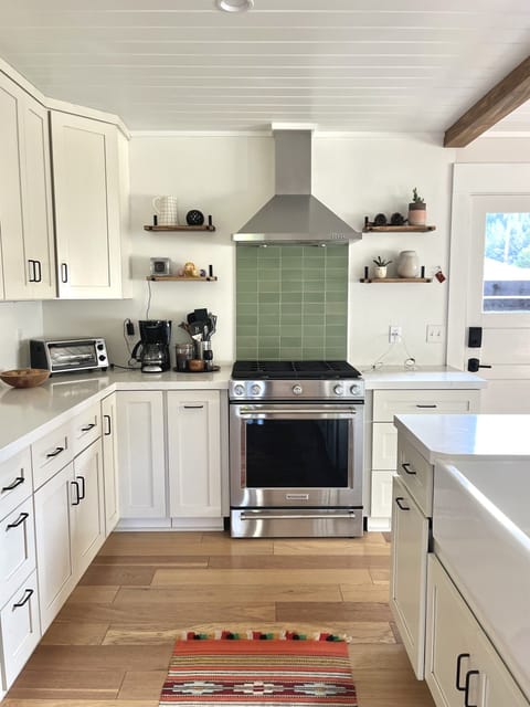 A galley kitchen with new stove and hood, lots of counter space, and All-Clad plans for gourmet meals.