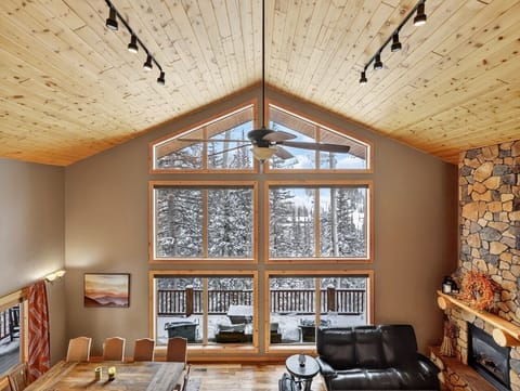 Relax in your cozy living space with soaring wood ceilings, a crackling fireplace, and stunning winter mountain views through floor-to-ceiling windows.