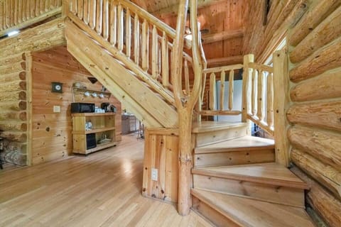 A log staircase leads to the Master Loft area that oversees the front area of the rustic designed cabin.