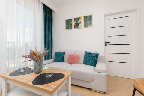 A cozy living room featuring a sofa with colorful cushions, a coffee table, and wall art.