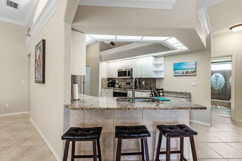 bar area (4 seats) looking back at kitchen with pool to back.
