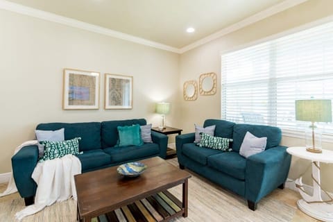 Cozy living room with teal sofas and natural light from a large window