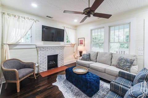 Living room space complete with sofa, coffee table, smart TV, fireplace, and ceiling fan.