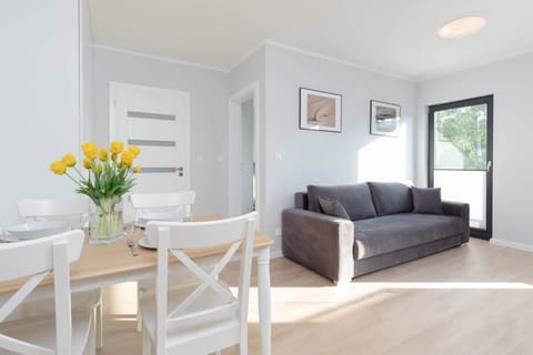 A cozy and bright living room with a comfortable sofa, a wooden coffee table, and natural light flooding in from large windows.
