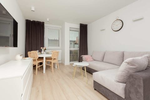 A bright and cozy living room with a large sofa, coffee table, and a dining area near the window, creating a welcoming space.
