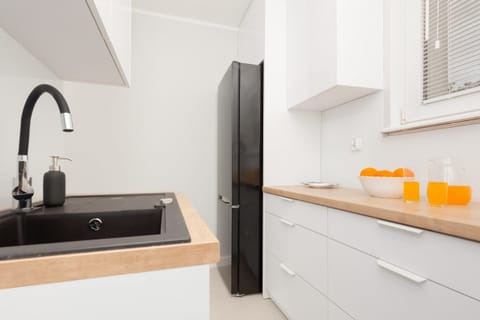 A close-up of the kitchen sink area with a stylish black faucet and bright accents of orange decor.
