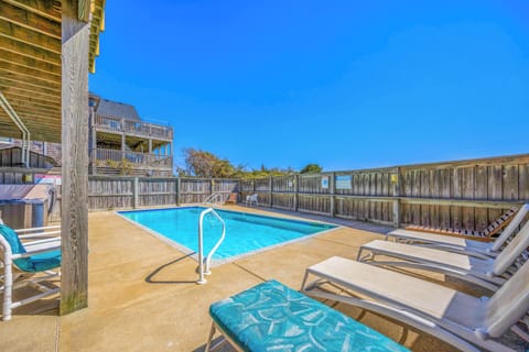 Sparkling pool surrounded by sunny loungers and coastal charm—perfect for lazy afternoons under endless blue skies. Your beachside retreat awaits.