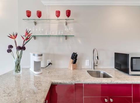 Kitchenette with microwave, mini fridge, Keurig coffee maker, glasses, plates, and cutlery
