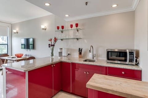 Kitchenette with microwave, mini fridge, Keurig coffee maker, glasses, plates, and cutlery
