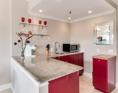 Kitchenette with microwave, mini fridge, Keurig coffee maker, glasses, plates, and cutlery
