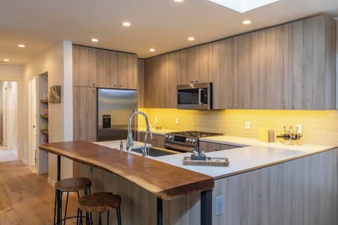 Modern, fully equipped kitchen with dish washer and a breakfast bar area.