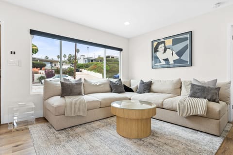 Living room is wide open with a large, custom sectional and original artwork. 