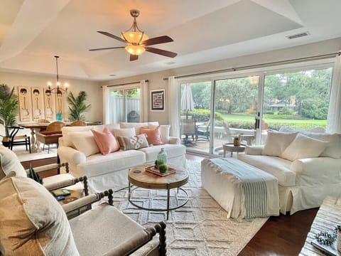Bright living room with comfortable seating and large sliding doors opening to a green outdoor view.
