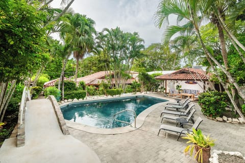 Enjoy the tropical shared swimming pool surrounded by lush gardens—perfect for a relaxing family vacation just steps from Tamarindo Beach.