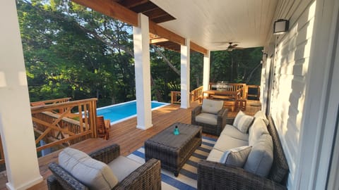 Outdoor space includes pool, lots of seating, gas BBQ and shower beneath a tree.