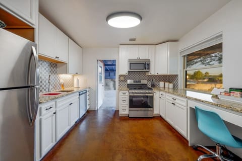 Updated kitchen with five-burner gas range, microwave, dishwasher, desk/workspace, granite countertops, and polished concrete floors