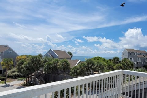 Step out here your first morning — Gulf through the palms, salt air, the whole week still ahead of you.