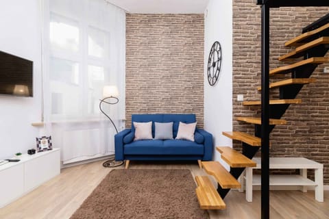 A cozy living room featuring a plush sofa and a simple coffee table. A large window allows natural light to fill the space.