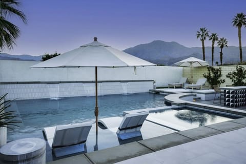 Sparkling pool w/ loungers, umbrella shade & peaceful mountain backdrop