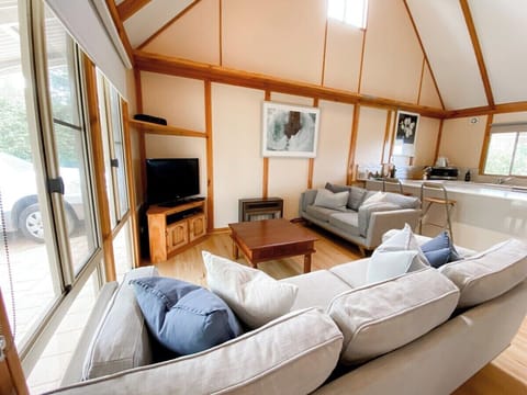The soaring timber-lined ceilings and open-plan layout create a warm, airy space for relaxing together after a day by the beach.