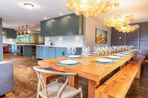 - Modern dining area with glowing chandeliers and long wood table for 12  
- Perfect for shared meals with open access to the kitchen and cozy seating  
- Warm lighting and stylish design create an inviting mountain gathering spot  
