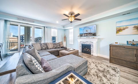 Spacious living room with a plush sectional, cozy fireplace, and balcony access.