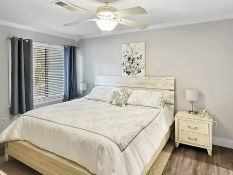  A generous bedroom featuring a king-sized bed with a whitewashed wood headboard.