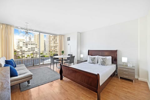 Bright studio with a queen bed, cozy sofa, and private balcony offering city views.