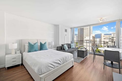 Bright studio with a queen bed, cozy sofa, and private balcony offering city views.