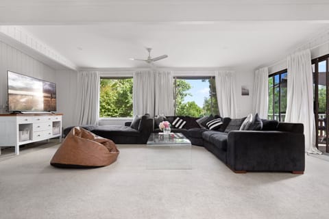 Spacious living room with huge couch, bean bags and 65-inch TV.
