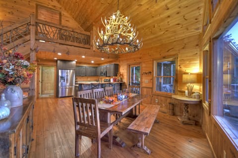 Rustic dining area with antler chandelier and wooden table.