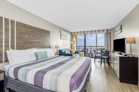 Lounge in seaside comfort in our studio suite, featuring a cozy bed and a stylish couch in the living area, creating an inviting space to unwind by the ocean.