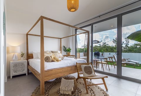 Unwind in your serene canopy bed retreat with private terrace access, where natural textures and gentle breezes create your perfect escape.