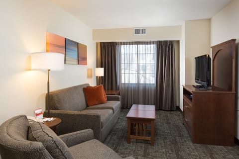 Gray sofa with an orange accent pillow and a floor lamp — the living area opens to the dining space