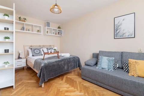 A cozy studio apartment featuring a bed integrated with shelves and a sofa for lounging.
