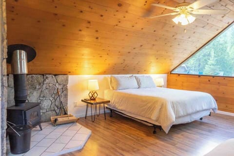 King size bed sits near the wood burning stove and the large window looking out to the trees

Linens are included in your stay